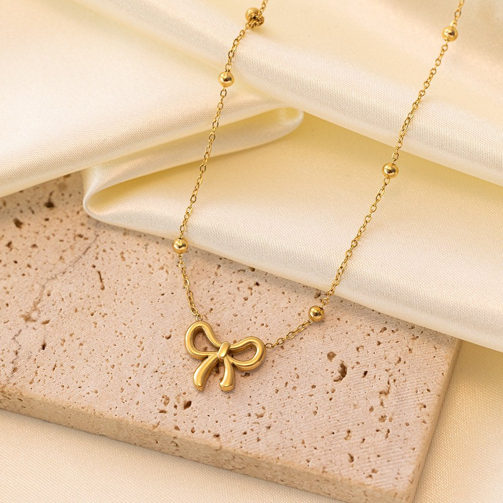 Gold bow pendant necklace with bead-accented chain,perfect for minimal and elegant styling